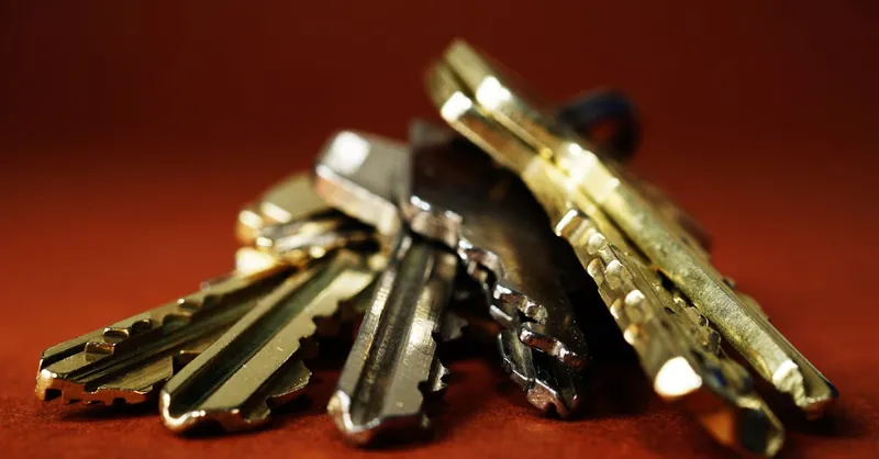 Detailed view of a pile of metallic keys on a deep red surface, emphasizing security and safety.