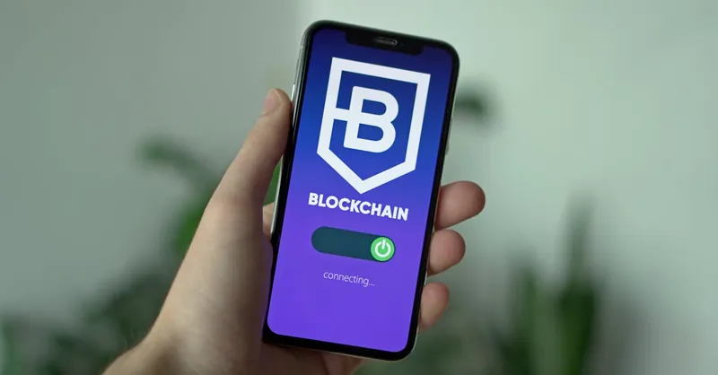 Close-up of a hand holding a smartphone with a blockchain app interface.