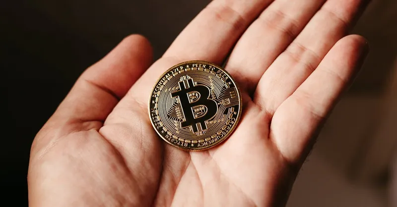 Close-up of a hand holding a Bitcoin coin, illustrating cryptocurrency concept.