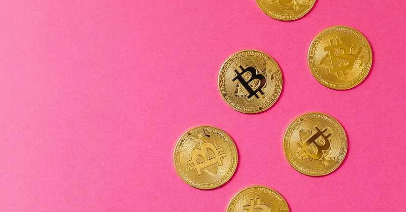 Gold Bitcoin coins on a vibrant pink surface, representing cryptocurrency and blockchain investment.