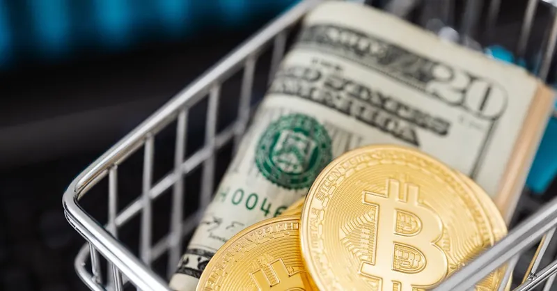 Close-up of bitcoin coins and US dollar bills in a small shopping cart, symbolizing online shopping and cryptocurrency investment.