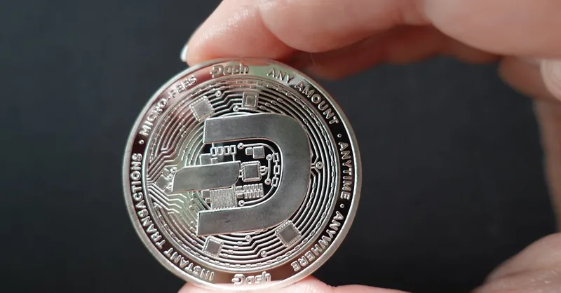 A close-up image showcasing a Dash coin held between fingers, emphasizing cryptocurrency and digital finance.