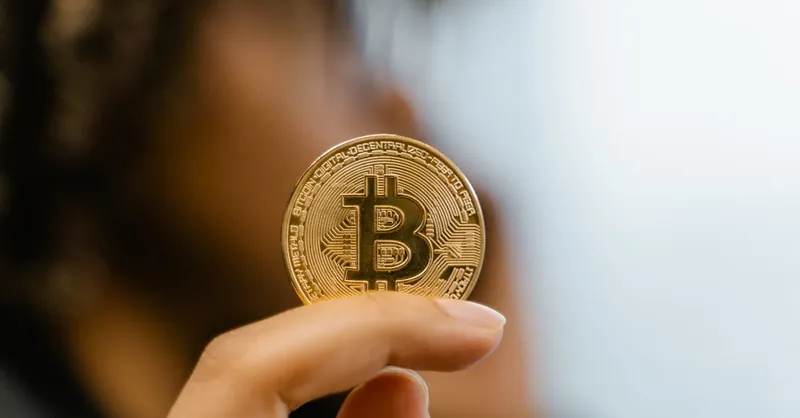 A hand holding a Bitcoin coin, representing cryptocurrency and blockchain technology investment.