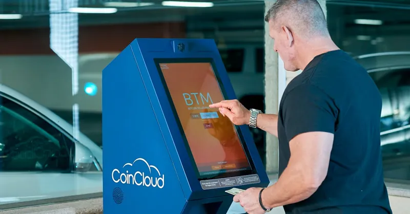 Man interacts with a CoinCloud Bitcoin ATM indoors, facilitating cryptocurrency exchange.