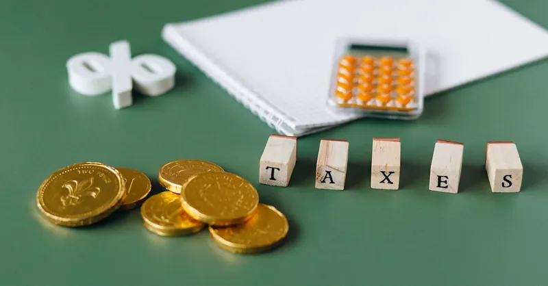 Close-up of tax-related items including coins, calculator, and word 