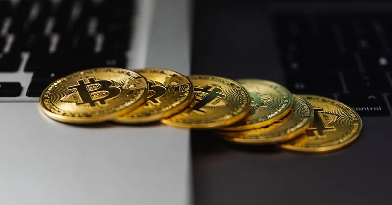 A stack of gold bitcoin coins placed on a laptop keyboard, symbolizing digital currency and finance.