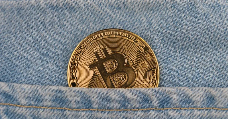 Close-up of a bitcoin coin in a denim pocket, symbolizing cryptocurrency and finance.