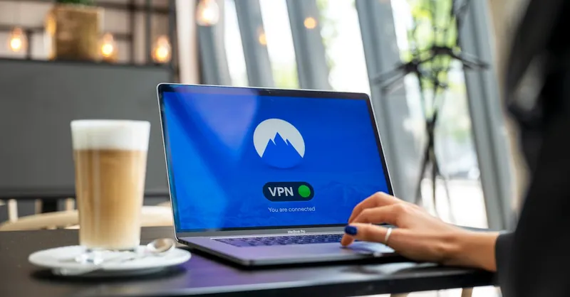 A person using a laptop with a VPN connection in a modern cafe setting, showcasing remote work and internet security.
