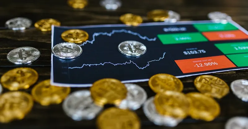 Bitcoin and altcoins on table with digital trading chart indicating market trends and investment details.