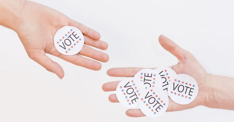 Close-up of hands holding election vote stickers, symbolizing participation.