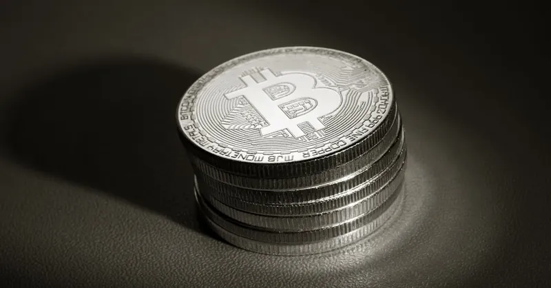 A stack of metallic Bitcoin cryptocurrency coins showcased on a dark surface, highlighting financial investment themes.