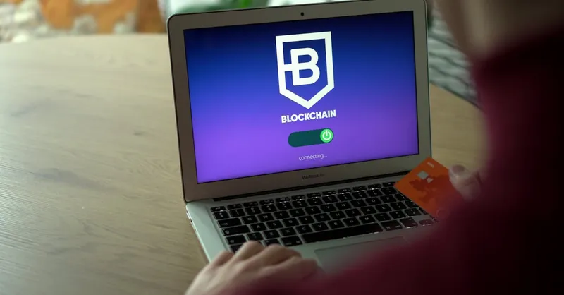 Person using laptop displaying blockchain login screen while holding card.
